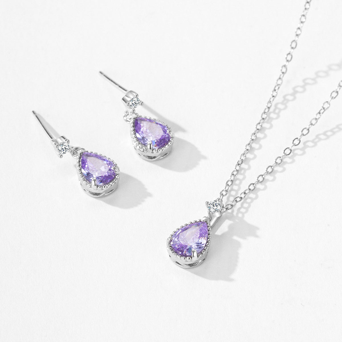 Jewelry set with purple teardrop stones on a white background