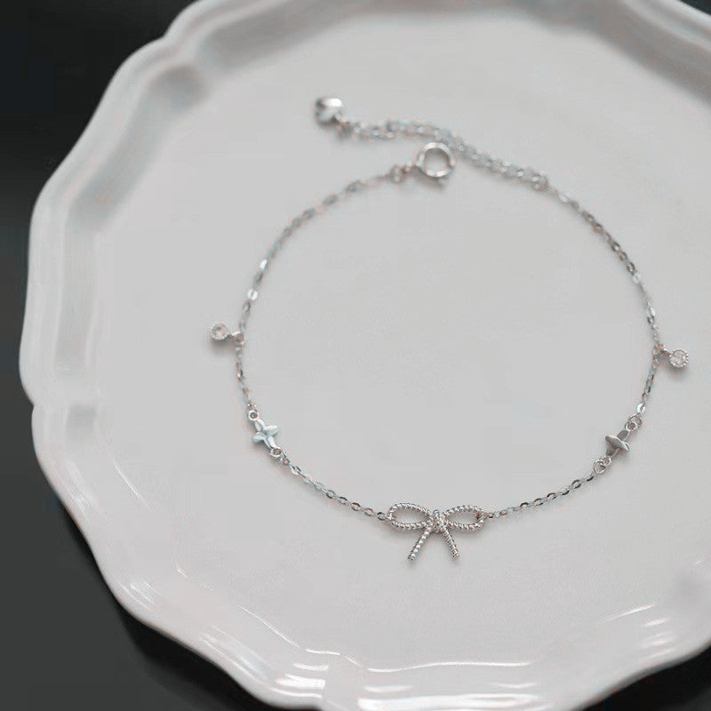 Silver bracelet with bow design on a white plate